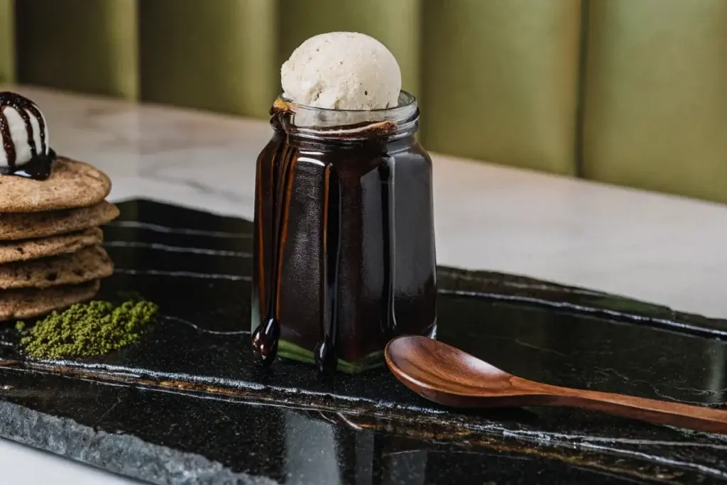 Homemade butterscotch syrup in a glass jar with dessert toppings.